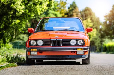 Brno, Çek Cumhuriyeti - 25 Ağustos 2024: Eski klasik klasik BMW 3 serisi spor arabası caddeye park edilmiş kırmızı renkli. Almanya 'da yapılmış bir ihtiyarın ön görüntüsü.