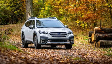 Güney Moravya, Çek Cumhuriyeti - 10 Kasım 2023: Sonbahar ormanlarında beyaz aile SUV Subaru Outback. Ağaçların ve yaprakların arasındaki off-road steyşın araba doğada bir yolculuğa çıktı..
