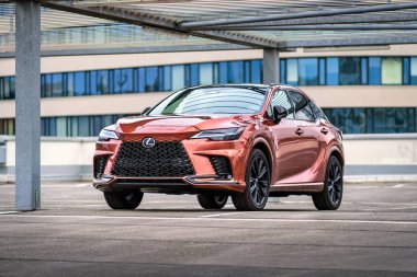 Brno, Çek Cumhuriyeti - 25 Ocak 2024: Orange Lexus RX SUV şehir merkezindeki modern binaların yakınına park etti. Japon lüks SUV hibrit sürücüsü ve 4x4.