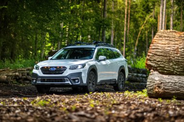 Güney Bohemya, Çek Cumhuriyeti - 12 Temmuz 2024: Beyaz aile arabası Subaru Outback ormandaki bir toprak yolda ağaçların arasında duruyor. Doğa gezisinde bir off-road arabası..