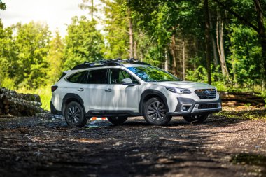 Güney Bohemya, Çek Cumhuriyeti - 12 Temmuz 2024: Beyaz aile arabası Subaru Outback ormandaki bir toprak yolda ağaçların arasında duruyor. Doğa gezisinde bir off-road arabası..
