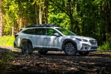 Güney Bohemya, Çek Cumhuriyeti - 12 Temmuz 2024: Beyaz aile arabası Subaru Outback ormandaki bir toprak yolda ağaçların arasında duruyor. Doğa gezisinde bir off-road arabası..