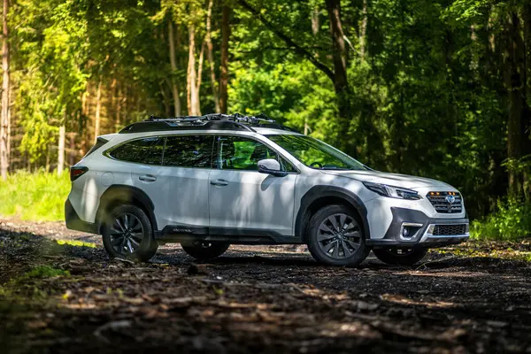 Güney Bohemya, Çek Cumhuriyeti - 12 Temmuz 2024: Beyaz aile arabası Subaru Outback ormandaki bir toprak yolda ağaçların arasında duruyor. Doğa gezisinde bir off-road arabası..