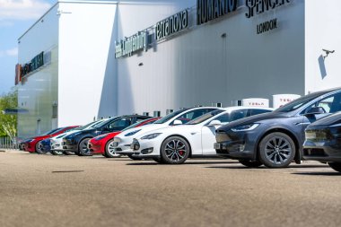 Brno, Çek Cumhuriyeti - 13 Mayıs 2025: Alışveriş merkezinin önünde bir sıra park edilmiş Tesla arabaları. Sahipleri alışveriş yaparken elektrikli arabalar pillerini şarj ediyor..