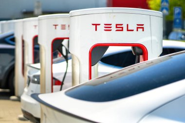 Brno, Çek Cumhuriyeti - 13 Mayıs 2025: Tesla şarj istasyonu şu anda bataryasını şarj eden bağlı bir araçla. Dışarıda bir otoparkta hızlı şarj istasyonu var..