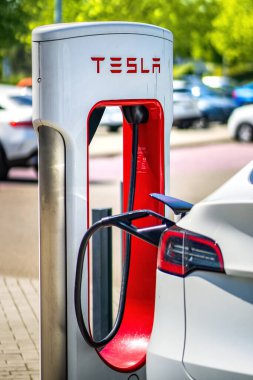 Brno, Çek Cumhuriyeti - 13 Mayıs 2025: Tesla şarj istasyonu şu anda bataryasını şarj eden bağlı bir araçla. Dışarıda bir otoparkta hızlı şarj istasyonu var..