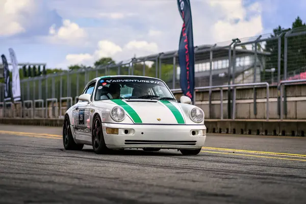 Brno, Çek Cumhuriyeti - 12 Ekim 2025: Beyaz klasik Porsche 911 tipi 964 1991 yarış pistinde hızlı sürüyor. Hızlı Alman çift kapılı coupe.