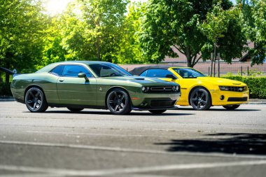 Brno, Çek Cumhuriyeti - 18 Mayıs 2025: Dışarıda park edilmiş iki Amerikan spor kaslı arabası. Yeşil Dodge Challenger ve sarı Chevrolet Camaro..