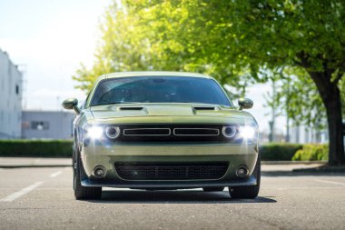 Brno, Çek Cumhuriyeti - 18 Mayıs 2025: Yeşil Amerikan Coupe Dodge Challenger açık havada ağaçların altındaki bir otoparkta park edilmiş. Şehirde mantar arabası var..