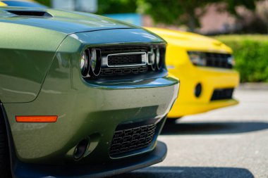 Brno, Çek Cumhuriyeti - 18 Mayıs 2025: Açık havada park edilmiş iki Amerikan spor kaslı arabası. Yeşil Dodge Challenger ve sarı Chevrolet Camaro. Farların ayrıntıları..