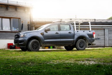 18 Ağustos 2024: Bir Ford Ranger SUV bir binanın önündeki dağlarda duruyor. Yatağı ve dahili kolu olan dört çekerli bir iş kamyonu dışarıda park halinde..