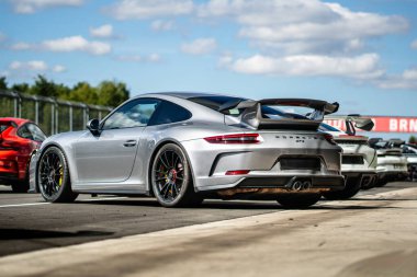 Brno, Çek Cumhuriyeti - 4 Eylül 2025: Gri Porsche 911 GT3 diğer Porsche arabaları arasında arka arkaya bir yarış pistinde park etti. Bir grup hızlı lüks Alman arabası..