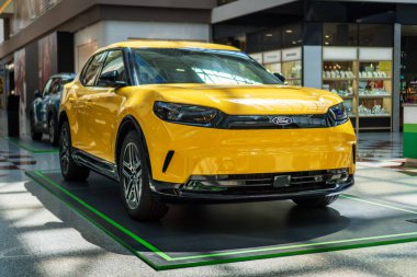 Brno, Çek Cumhuriyeti - 10 Haziran 2025: Sarı elektrikli SUV Ford Capri bir alışveriş merkezinde duruyor. Arabanın ön tarafının ışıkları ve tamponu var..