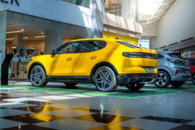 Brno, Çek Cumhuriyeti - 10 Haziran 2025: Sarı elektrikli SUV Ford Capri bir alışveriş merkezinde duruyor. Arabanın yan görüntüsü..