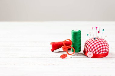 El yapımı ve dikiş arka planı. Dikiş aksesuarları, makara, iğne, makas, beyaz ahşap arka planda dikiş işi için düğme. Dikiş aletleri ve malzemeler. Boşluğu Kopyala