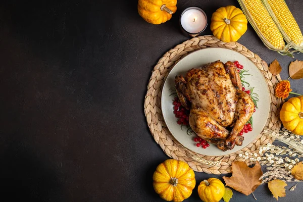 Happy Thanksgiving holiday background. Roasted whole chicken or turkey with autumn vegetables for thanksgiving dinner on dark background. Copy spac