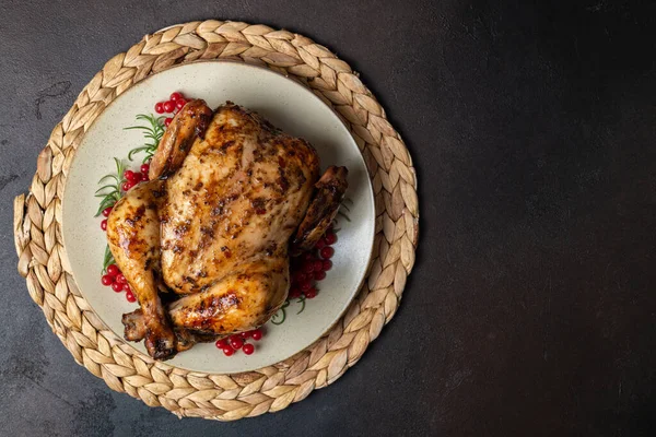 Roasted chicken for festive dinner. Cooked chicken or turkey with herb rosemary and berries on dark table. Dish for Thanksgiving, Christmas holiday concept. Copy space