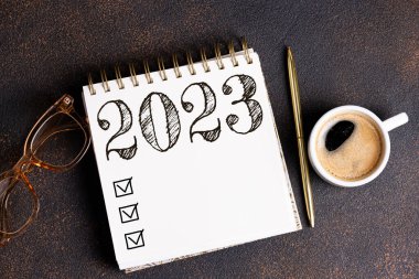 2023 sayılı yeni yıl kararları masada. Not defteri ve kahve fincanı olan 2023 karar listesi. Hedefler, çözümler, plan, eylem, kontrol listesi konsepti. Yeni Yıl 2023 şablonu, Spac kopyala
