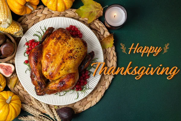 Happy Thanksgiving holiday background. Roasted whole chicken or turkey with autumn vegetables for thanksgiving dinner on dark table. Thanksgiving card
