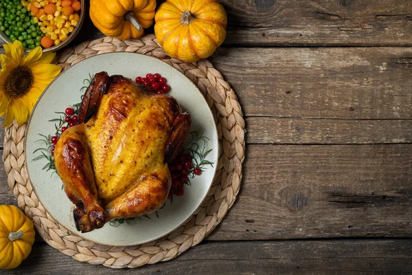 Happy Thanksgiving holiday background. Roasted whole chicken or turkey with autumn vegetables for thanksgiving dinner on wooden table. Copy space