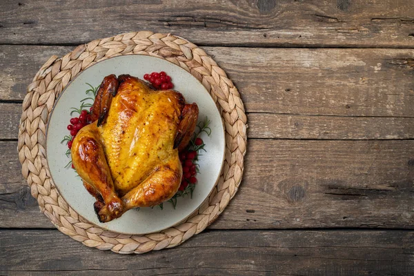 Roasted chicken for festive dinner. Cooked chicken with herb rosemary and berries on wooden table. Dish for Thanksgiving, Christmas holiday concept. Copy spac