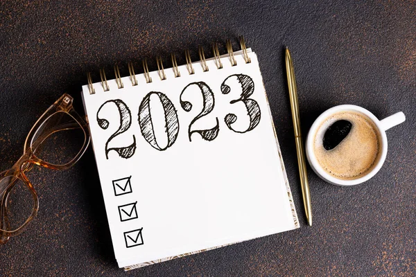 New year resolutions 2023 on desk. 2023 resolutions list with notebook, coffee cup on table. Goals, resolutions, plan, action, checklist concept. New Year 2023 template, copy spac