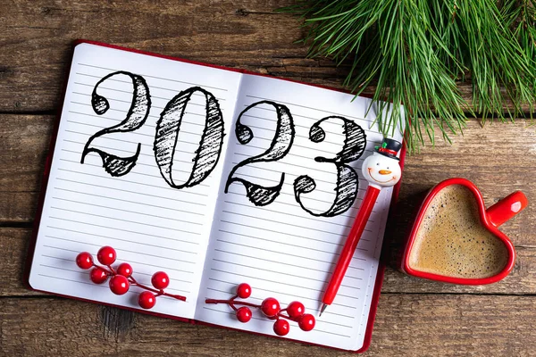 New year resolutions 2023 on desk. 2023 resolutions list with notebook, coffee cup, decorations on table. Goals, resolutions, plan, action concept. New Year 2023 background. Copy spac