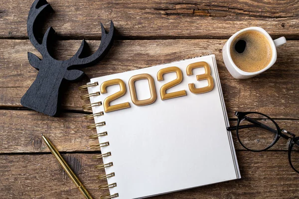 New year resolutions 2023 on desk. 2023 resolutions list with notebook, coffee cup on table. Goals, resolutions, plan, action concept. New Year 2023 background. Copy spac