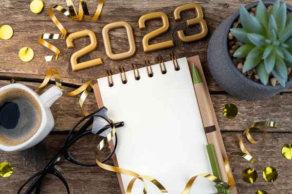New year resolutions 2023 on desk. Festive background 2023 resolutions with notebook, coffee cup on table. Goals, resolutions, plan, action concept. New Year 2023 holiday, copy spac