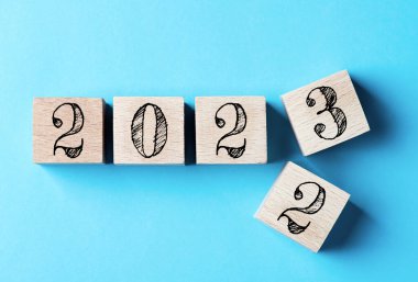 2023 mutlu yıllar. 2022 'den 2023' e kadar mavi üzerine tahta blok değişimi. 2023 Yılbaşı Gecesi kavramı. İş, kararlar, hedefler, ilham, başarı, fikirler