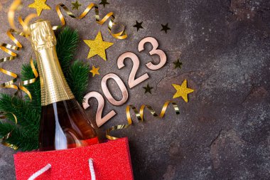 2023 yılbaşı arkaplanı. İçinde bir şişe şampanya olan yeni yıl kartı, şenlikli süslemeler. Hediye, 2023 yılbaşı hediyesi. Uzun biçim, boşluğu kopyala