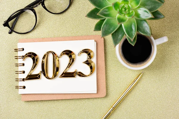 New year resolutions 2023 on desk. 2023 resolutions list with notebook, coffee cup on golden background. Goals, resolutions, plan, action, checklist concept. New Year 2023 template, copy spac