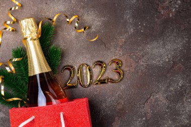 2023 yılbaşı arkaplanı. İçinde bir şişe şampanya olan yeni yıl kartı, şenlikli süslemeler. Hediye, 2023 yılbaşı hediyesi. Uzun biçim, boşluğu kopyala