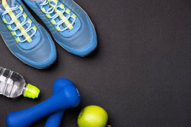 Sport shoes and equipment for fitness healthy lifestyle, exercise, healthy food concept. Motivation sport goals card with sport equipment shoes, dumbbells, fruit and water bottle on black backgroun