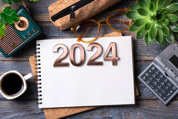 New year resolutions 2024 on desk. 2024 goals list with notebook, coffee cup, plant on wooden table. Resolutions, plan, goals, action, checklist, idea concept. New Year 2024 resolutions, copy spac