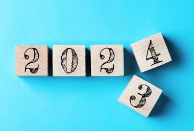 2024 Mutlu Yıllar. 2023 'ten 2024' e kadar mavi üzerine tahta blok değişimi. 2024 Yeni Yıl geçmişi kavramı. İş, kararlar, hedefler, ilham, başarı, fikirler