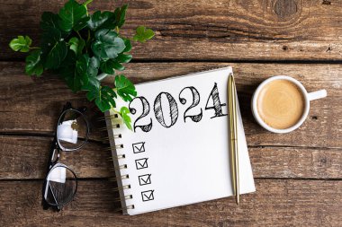2024 sayılı yeni yıl kararları masada. 2024 gol listesi, defter, kahve fincanı, ahşap masa. Kararlar, plan, hedefler, eylem, kontrol listesi, fikir konsepti. Yeni Yıl 2024 kararları, kopyalama alanı