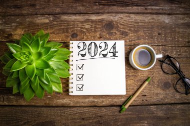 2024 sayılı yeni yıl kararları masada. 2024 gol listesi, defter, kahve fincanı, ahşap masa. Kararlar, plan, hedefler, eylem, kontrol listesi, fikir konsepti. Yeni Yıl 2024 kararları, kopyalama alanı