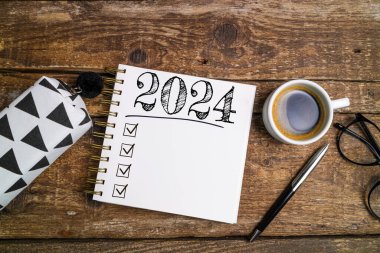 2024 sayılı yeni yıl kararları masada. 2024 gol listesi, defter, sehpada kahve fincanı. Kararlar, plan, hedefler, eylem, kontrol listesi, fikir konsepti. Yeni Yıl 2024 kararları, kopyalama alanı