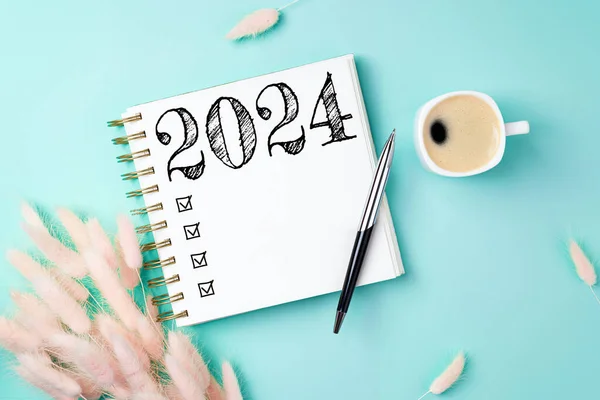 New year resolutions 2024 on desk. 2024 resolutions list with notebook, coffee cup on yellow table. Goals, resolutions, plan, action, checklist concept. New Year 2024 template, copy spac