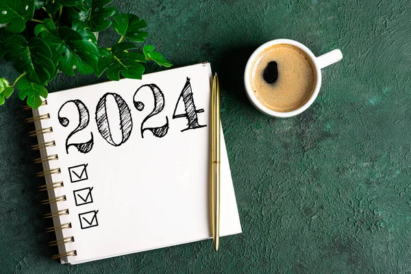 新年の決議2024が机の上に ノートブック付き2024解像度リスト テーブルにコーヒーカップ チェックリストのコンセプト 新年2024テンプレート コピースペース — ストック写真