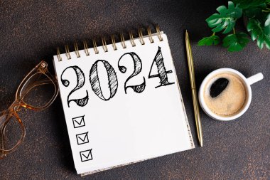 2024 sayılı yeni yıl kararları masada. 2024 gol listesi, defter, kahve fincanı, masada bitki. Kararlar, plan, hedefler, eylem, kontrol listesi, fikir konsepti. Yeni Yıl 2024 kararları, kopyalama alanı