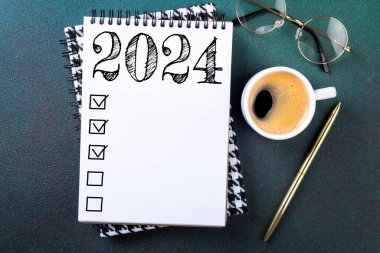 2024 sayılı yeni yıl kararları masada. Not defteri ve kahve fincanı olan 2024 karar listesi. Hedefler, çözümler, plan, eylem, kontrol listesi konsepti. Yeni Yıl 2024 şablon, kopyalama alanı