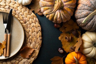 Cozy hygge table. Top view of plate and cutlery, pumpkins, autumn leaves on dark table. Autumn table setting. Festive Thanksgiving or Halloween background. Restaurant menu. Copy spac clipart