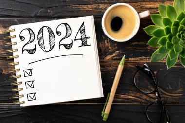 2024 sayılı yeni yıl kararları masada. Not defterli 2024 karar listesi, ahşap masadaki kahve fincanı. Hedefler, çözümler, plan, eylem, kontrol listesi konsepti. Yeni Yıl 2024 şablon, Spac kopyala