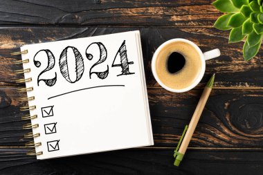 2024 sayılı yeni yıl kararları masada. 2024 gol listesi, defter, kahve fincanı, ahşap masa. Kararlar, plan, hedefler, eylem, kontrol listesi, fikir konsepti. Yeni yıl 2024 kararları. Boşluğu kopyala