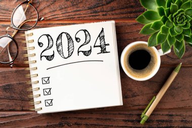 2024 sayılı yeni yıl kararları masada. 2024 gol listesi, defter, kahve fincanı, ahşap masa. Kararlar, plan, hedefler, eylem, kontrol listesi, fikir konsepti. Yeni yıl 2024 kararları. Boşluğu kopyala