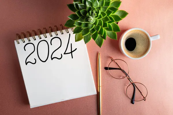 2024 New year resolutions on desk. 2024 goals list with notebook, coffee cup, plant on pink table. Resolutions, plan, goals, action, idea concept. New Year 2024 resolutions. Copy space