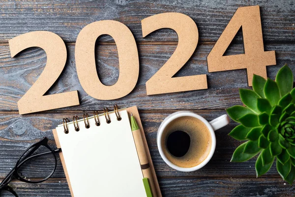 New year resolutions 2024 on desk. 2024 resolutions list with notebook, coffee cup on wooden table. Goals, resolutions, plan, action, checklist concept. New Year 2024 template, copy space