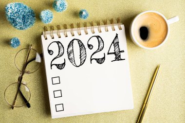 2024 yeni yıl kararı masada. 2024 gol listesi, defter, kahve fincanı, altın arka planda şenlik süslemeleri. Çözümler, plan, hedefler, kontrol listesi, fikir konsepti. Yeni yıl 2024 kararları. Boşluğu kopyala